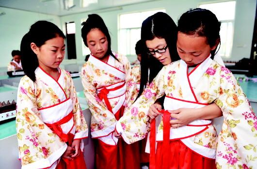 韩玲玲为参加公益演出的学生穿戴汉服,教她们如何给腰带打结.