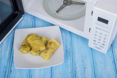 白色微波炉,在蓝色的木质表面加热食物图片