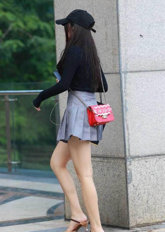 小姐姐的黑色棒球帽很是个性，黑色的上衣搭配灰色百褶裙，显瘦又减龄。
