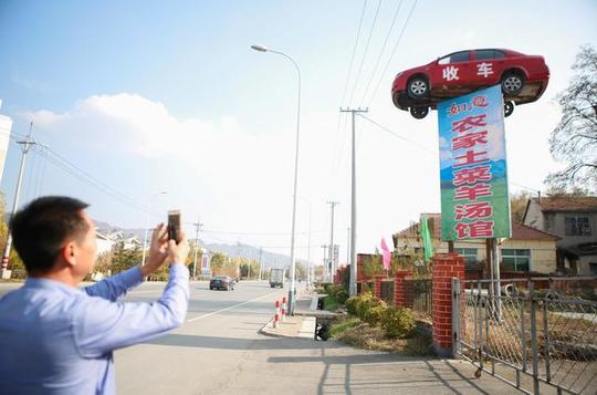 据附近居民介绍,这是一个饭店的广告牌,这家饭店老板同时经营手车生意