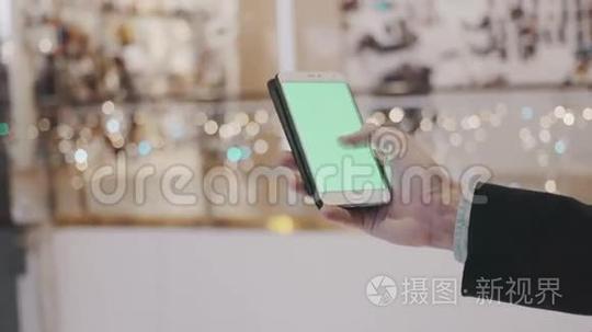 男性手使用智能手机与绿色屏幕在购物中心。背景节日装饰品短视频