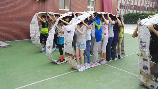 同学们以小组为单位,全员站到想履带一样的报纸车轮里,用手推动履带全