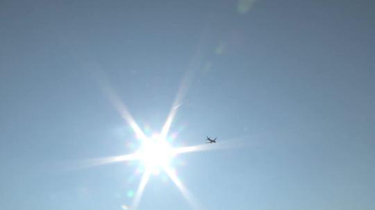 仰拍空中飞机飞行飞过太阳_1920x1080_高清视频素材