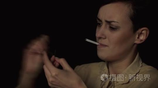 试图用一根火柴点烟的年轻女人。她不能光香烟，黑色背景