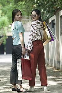 女性闺蜜在小路上逛街购物图片下载