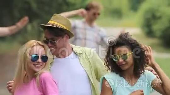 可爱的家伙和两个随意的女孩在户外聚会上跳舞，双手放在腰间短视频