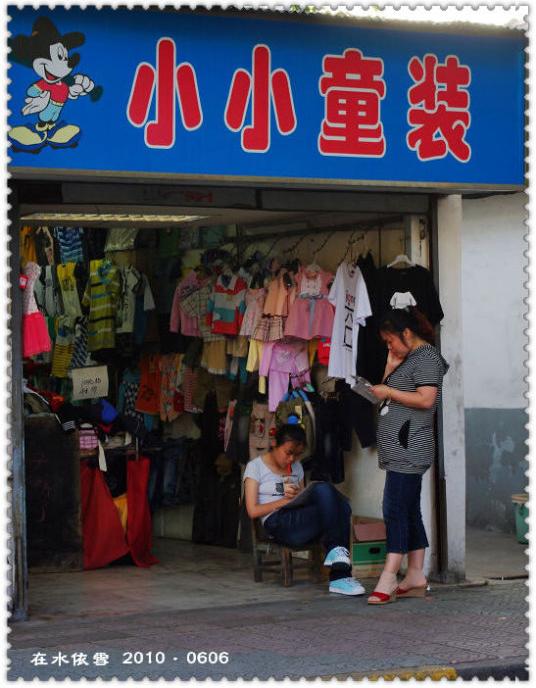童装店的小姑娘老板,似乎也不着急做生意,喝着奶茶看着感兴趣的书籍
