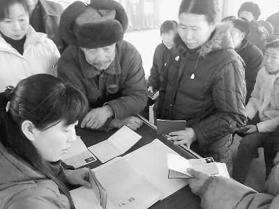 图为农村低保对象在凭证领取低保金-伊春建立困难党员创业扶助机制