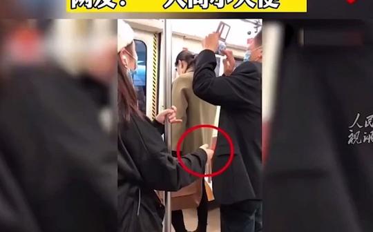 四川成都，一老人在地铁上用手机拍路线图，旁边女孩一直把手放在老人后面，怕其摔倒。