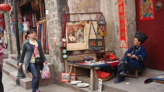 苗家阿婆身着民族服装,守在自家门前做点小生意.