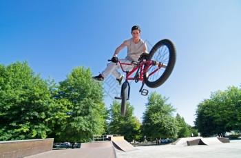 在溜冰场的铁管斜坡上玩尾鞭的bmx骑手图片下载