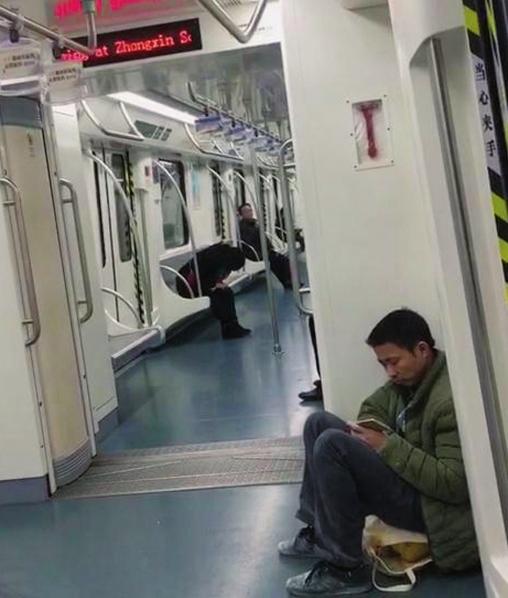 泥印的男子坐在车厢的地上.图/易先生-地铁有座不坐大叔说身上太脏