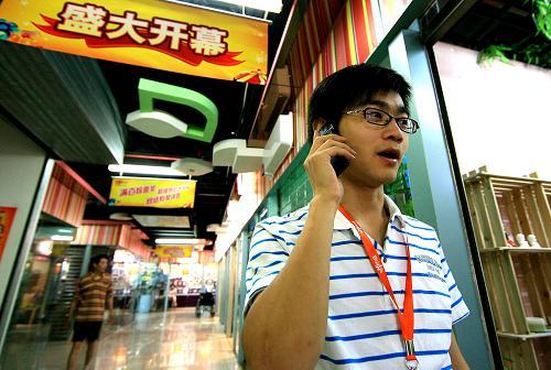 7月4日，武汉大学毕业生张斌(右)正在电话联系供货商，他自己开设的工艺蜡烛饰品店刚刚开张。自7月1日起，上海市普陀区采用新模式举办大学生创业见习大赛，向有志于经商的大学生在中心城区提供200间免租一年的店铺做生意，