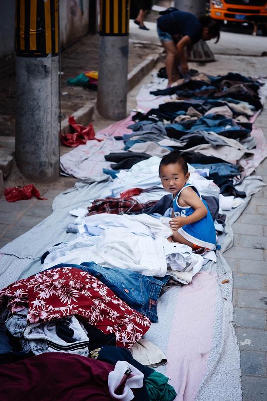 小家伙跟着卖二手衣服的妈妈出来摆摊,当妈妈忙着做生意的时候,他就在