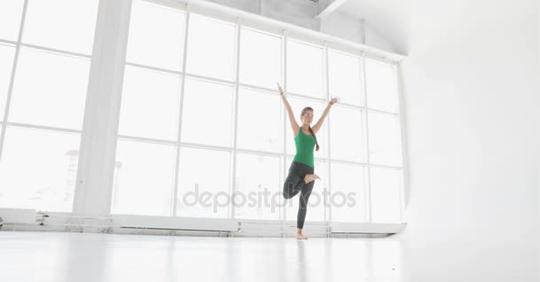 在窗口拉伸年轻漂亮的女人。年轻女子练习瑜伽动作和职位的一个摄影棚里短视频