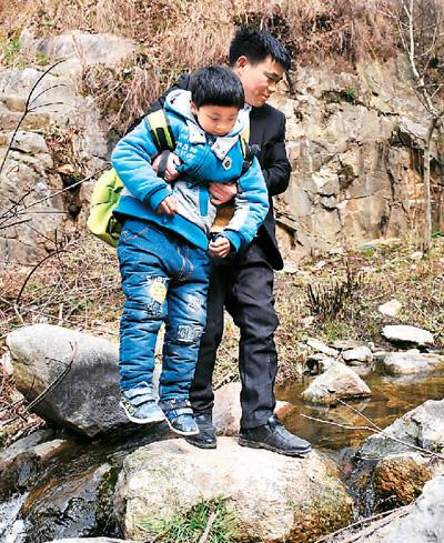放学路上,张玉滚抱起一名学生过溪.-乡下娃的读书引路人