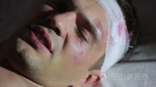 头部受伤躺在床上的男人。护士照顾受伤的男人短视频