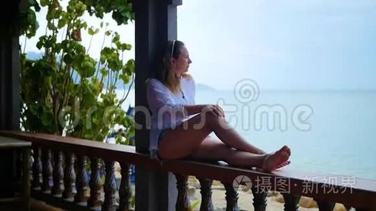 女孩坐在露台上朝大海看