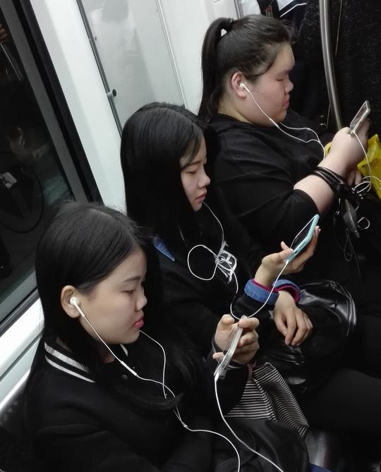地铁里,三女孩看手机.