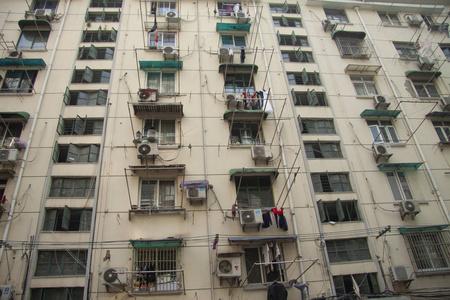 北京现代农村的住宅建筑窗户和阳台上挂着大量的空调和衣服。图片