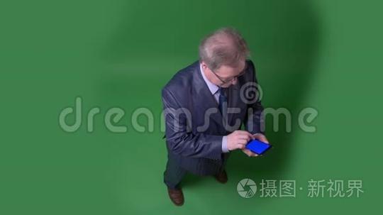 全高镜头的高级男子打开应用程序，显示蓝色屏幕的手机绿色色度背景。短视频