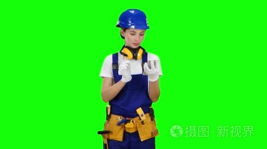 女孩建设者看她的智能手机照片的建筑,为未来的工作。绿屏短视频