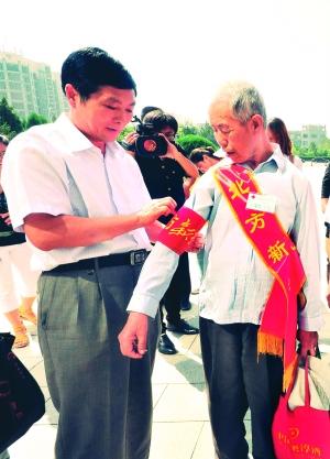 北方新报社社长相恒义(左)为李逢春老人佩戴袖章