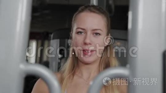 一个身材漂亮的运动女性在健身房的模拟器上训练胸肌。