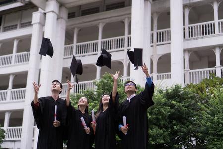 一群成功的同学一起祝贺,一起扔在空中的毕业帽和庆祝。教育理念图片