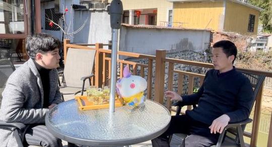 实践队员与安吉余村“春林山庄”主人潘春林(右)交谈