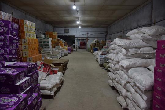 即将配送到超市的食品,日用品在仓库里整齐罗列,分拣员按照手里分拣单