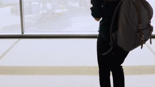 女孩与背包步行到机场休息室窗口。有智能手机的女乘客在候机楼等候。商人.4k短视频