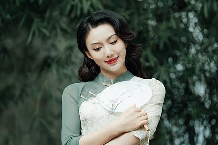 在园林里手拿扇子的旗袍美女图片下载