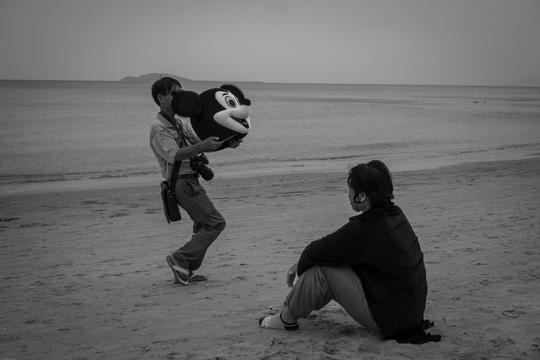 打扮成米老鼠与游人拍照挣钱的女人在海滩上休息,给游人拍照挣钱的