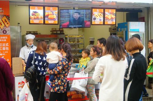 深圳某面包店美女员工站台销售生意好，顾客排长长队伍等候购买