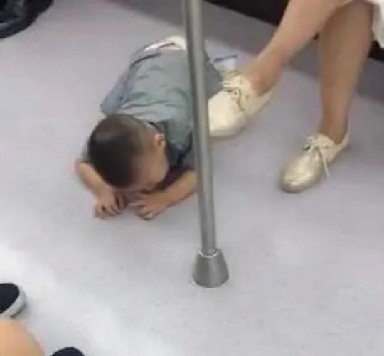 地铁上男孩趴在地上睡觉，妈妈悠闲玩手机，看到男孩手后乘客报警