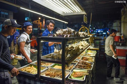 印尼夫妻档经营的路边摊，食客席地而吃，每天收入1000多万